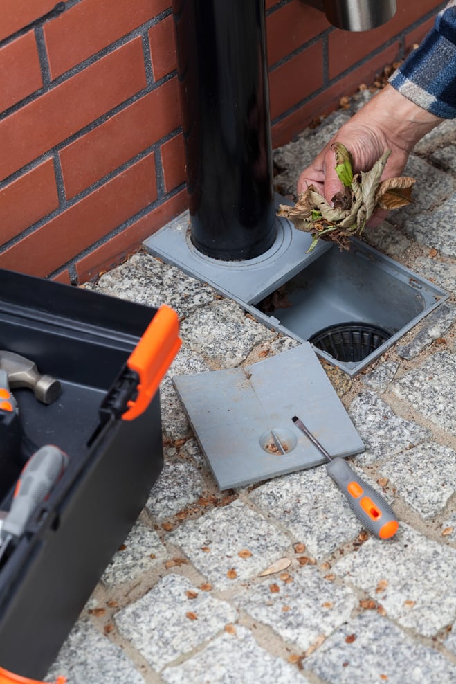 Elderly man cleans the gutter outside